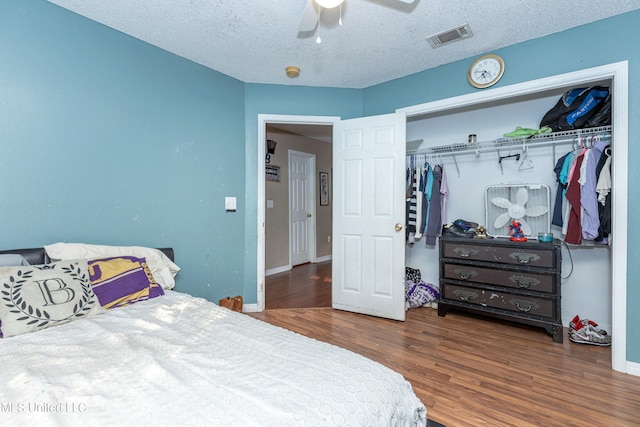 bedroom with a textured ceiling, wood-type flooring, a closet, and ceiling fan