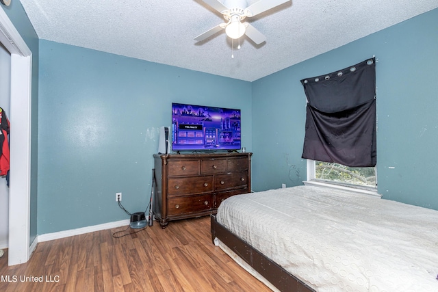 bedroom featuring a textured ceiling, a ceiling fan, wood finished floors, and baseboards