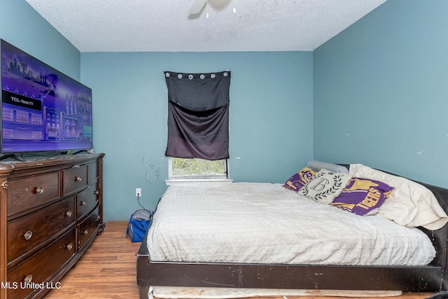 bedroom with light hardwood / wood-style floors, a textured ceiling, and ceiling fan