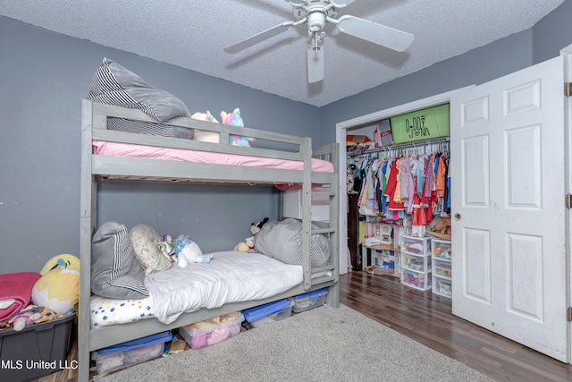 bedroom featuring dark wood-type flooring, ceiling fan, a closet, and a textured ceiling