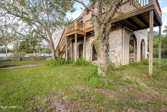 exterior space with a yard, brick siding, fence, stairway, and a wooden deck