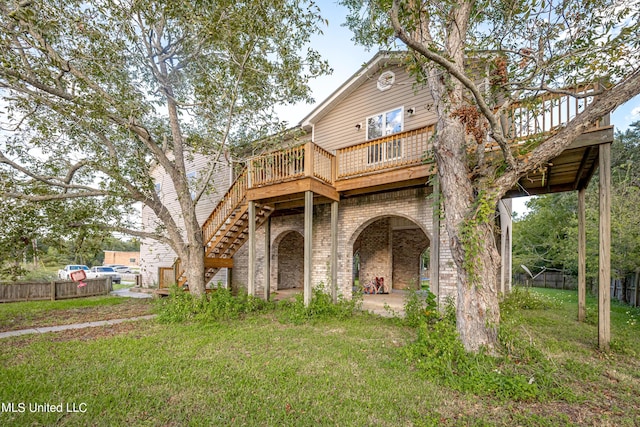 view of front of home with a deck, stairway, fence, and a front lawn