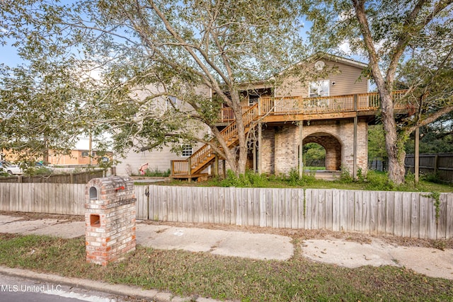 view of front of house featuring a deck, brick siding, fence private yard, and stairs