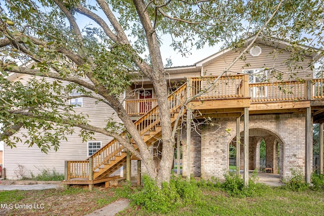 back of property featuring a deck, stairway, brick siding, and a patio area