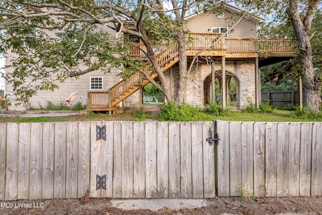 rear view of property featuring stairway, brick siding, fence private yard, and a wooden deck