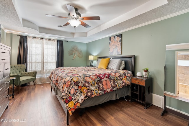 bedroom with a raised ceiling, ceiling fan, and hardwood / wood-style floors