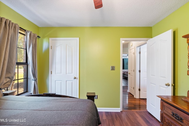 unfurnished bedroom featuring a textured ceiling, ceiling fan, and dark wood-type flooring