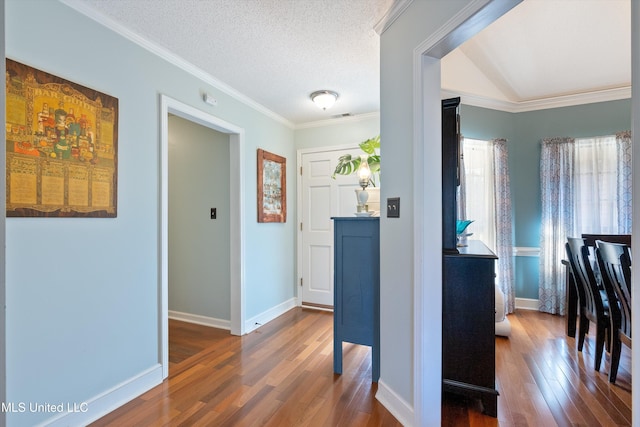 corridor featuring dark wood-type flooring, a textured ceiling, and ornamental molding