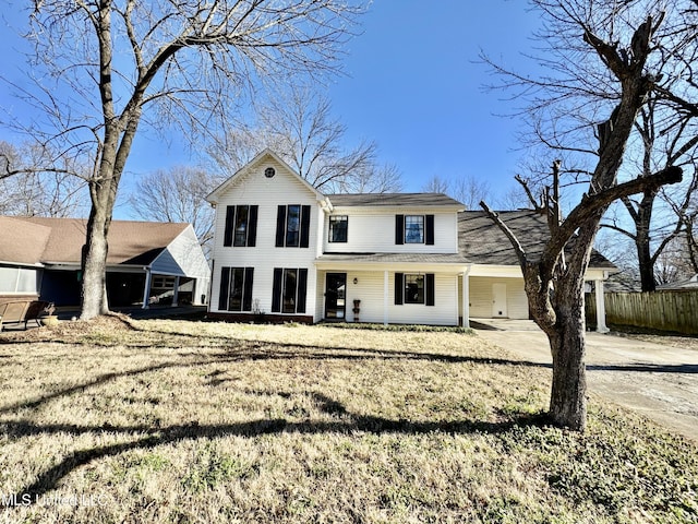 view of front facade with driveway, fence, and a front lawn