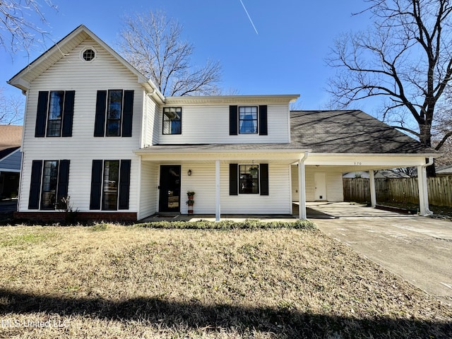 traditional-style house featuring an attached carport, fence, and driveway