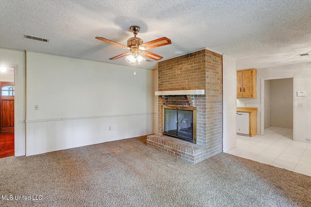 unfurnished living room featuring ceiling fan, a textured ceiling, light tile patterned floors, and a brick fireplace