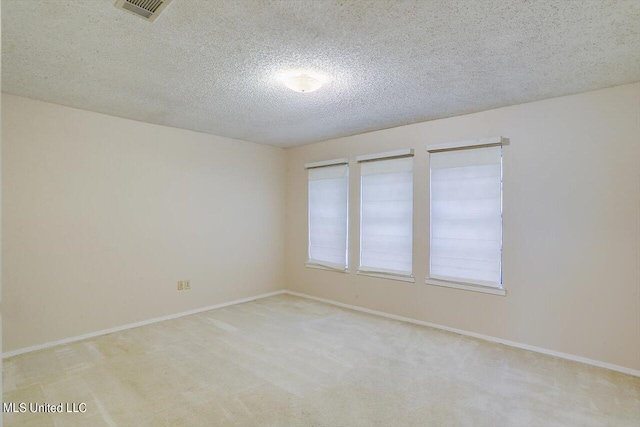 spare room with a textured ceiling and light colored carpet