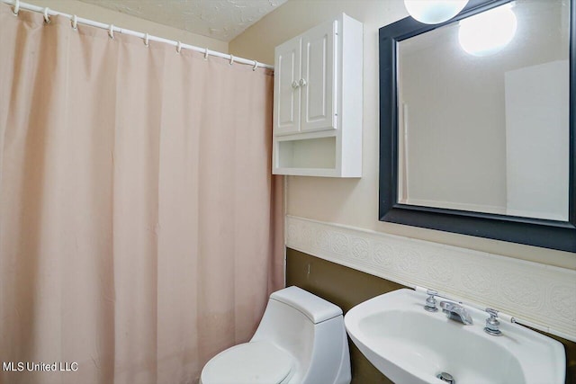 bathroom with toilet, a textured ceiling, sink, and a shower with curtain