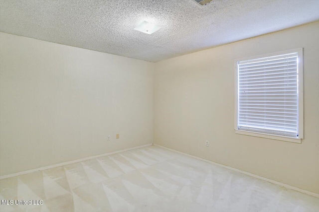 empty room featuring a textured ceiling and light colored carpet