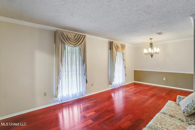 unfurnished room with ornamental molding, a notable chandelier, a textured ceiling, and hardwood / wood-style flooring