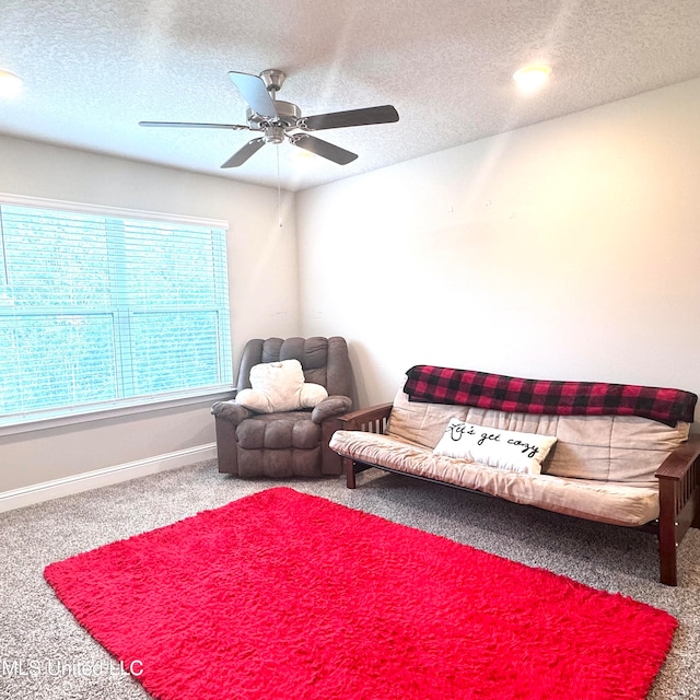 living room featuring a textured ceiling, carpet flooring, and ceiling fan