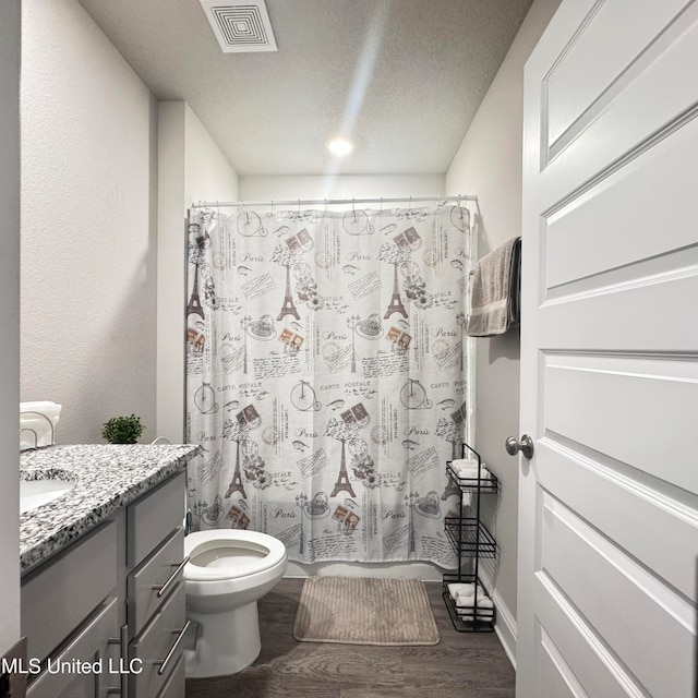 bathroom with a shower with curtain, vanity, a textured ceiling, hardwood / wood-style flooring, and toilet