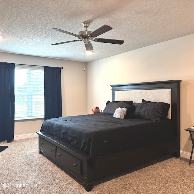 bedroom with a textured ceiling, light colored carpet, and ceiling fan