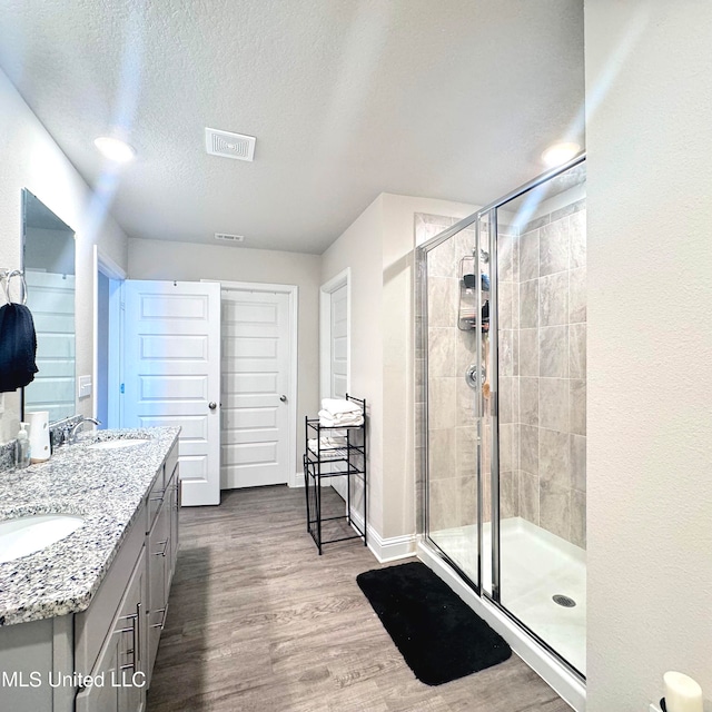 bathroom featuring hardwood / wood-style floors, vanity, a textured ceiling, and a shower with door