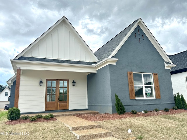 view of front of house with a front yard, french doors, and covered porch