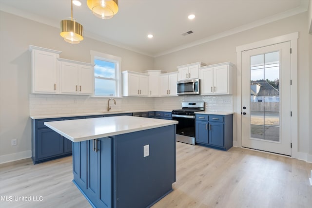 kitchen featuring appliances with stainless steel finishes, blue cabinetry, a center island, and plenty of natural light