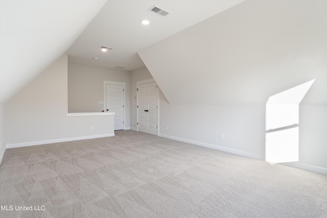 additional living space featuring lofted ceiling and light carpet