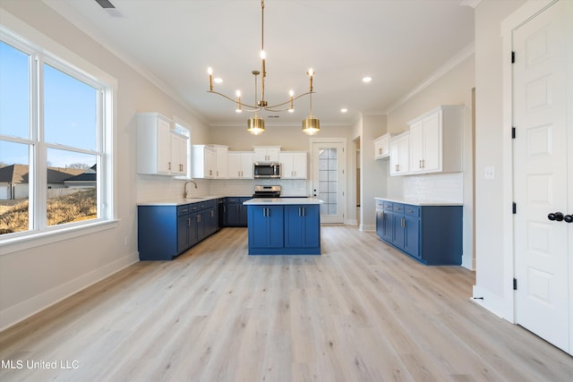 kitchen with ornamental molding, white cabinets, pendant lighting, blue cabinets, and appliances with stainless steel finishes