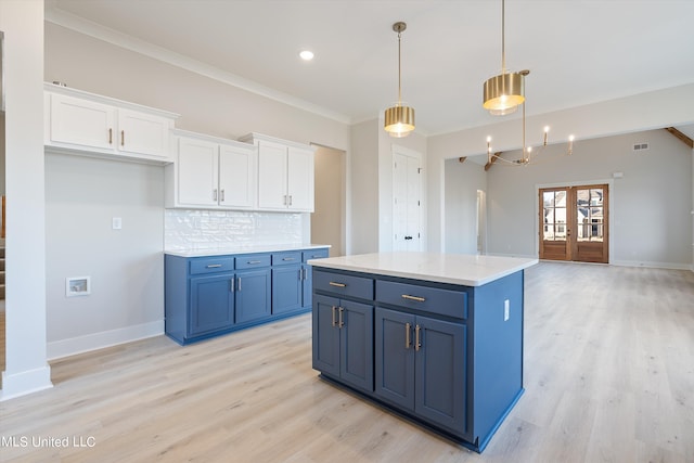 kitchen with white cabinets, a kitchen island, ornamental molding, pendant lighting, and french doors