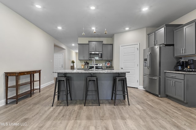 kitchen featuring baseboards, light wood-style flooring, appliances with stainless steel finishes, and gray cabinetry