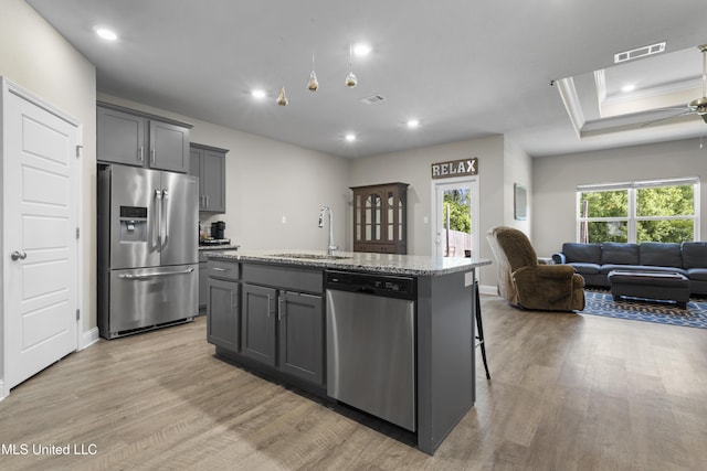 kitchen featuring appliances with stainless steel finishes, a sink, light wood-style flooring, open floor plan, and visible vents