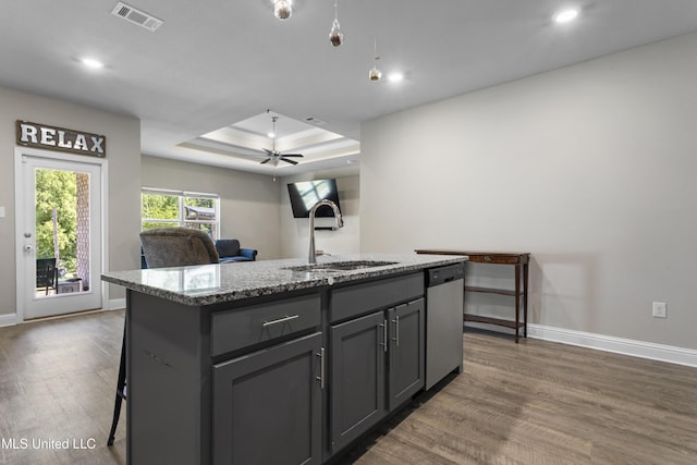 kitchen with visible vents, dishwasher, a sink, a raised ceiling, and dark wood-style floors