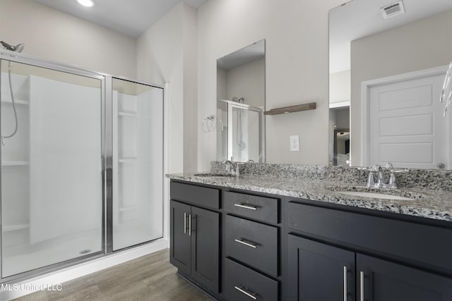 full bathroom with visible vents, a shower stall, a sink, and wood finished floors