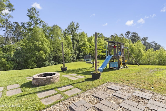 view of playground featuring a lawn and an outdoor fire pit