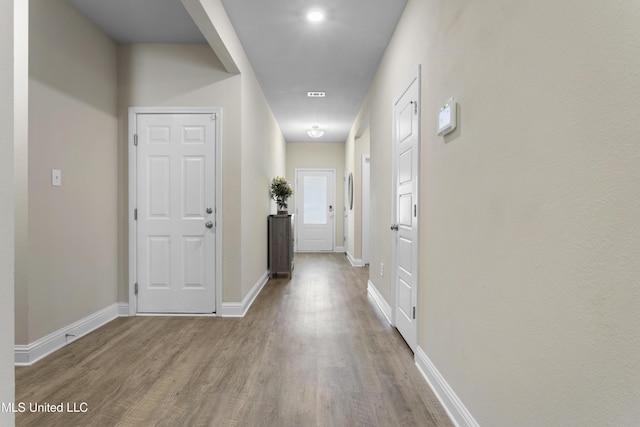 corridor with baseboards and wood finished floors
