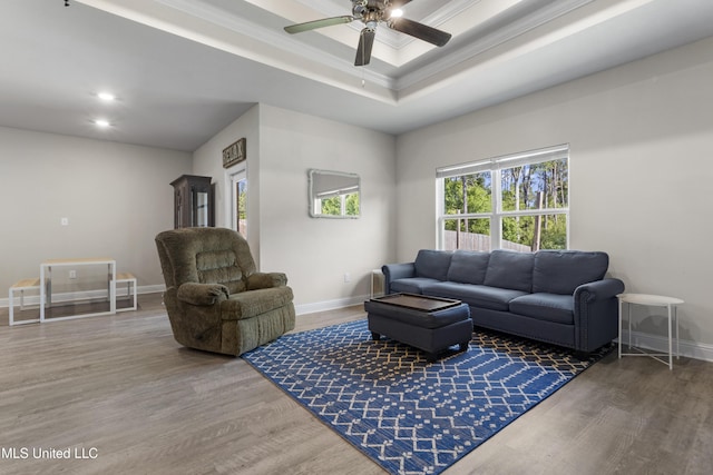 living room with crown molding, a ceiling fan, baseboards, wood finished floors, and a tray ceiling