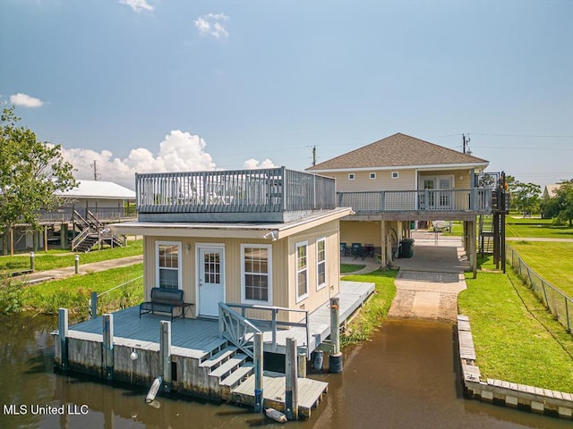 back of house with a deck with water view and a yard