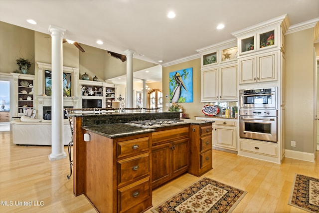 kitchen featuring dark stone countertops, appliances with stainless steel finishes, a center island, and light wood-type flooring