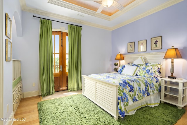 bedroom featuring ceiling fan, a raised ceiling, ornamental molding, and light hardwood / wood-style flooring