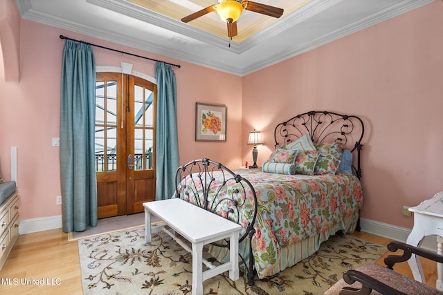 bedroom featuring ceiling fan, crown molding, light hardwood / wood-style flooring, and a tray ceiling