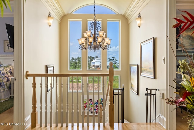 interior space with an inviting chandelier, hardwood / wood-style flooring, crown molding, and a wealth of natural light