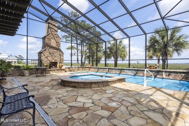 view of pool with an in ground hot tub, a patio area, an outdoor stone fireplace, and glass enclosure