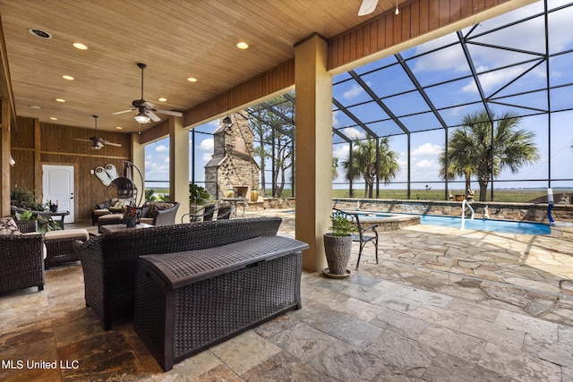 view of patio featuring ceiling fan, a lanai, and an outdoor living space with a fireplace