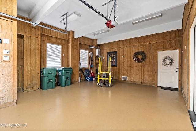 garage featuring a garage door opener and wooden walls