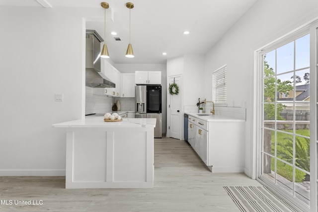 14789 Nassau Dr, Biloxi, MS 39532 - kitchen with appliances with stainless steel finishes, wall chimney exhaust hood, a peninsula, tasteful backsplash, and white cabinetry