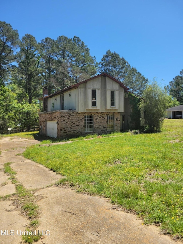 view of property exterior featuring brick siding, a lawn, a chimney, a garage, and driveway
