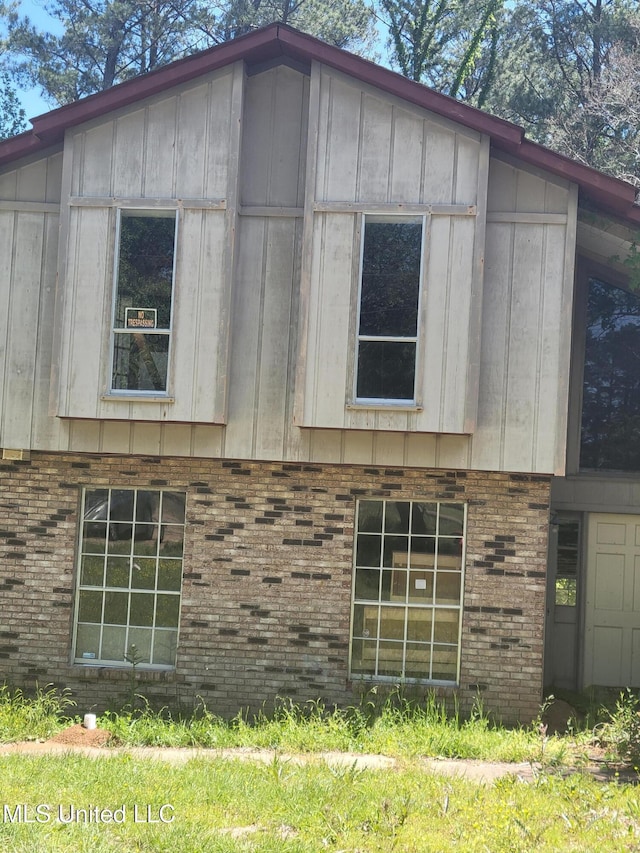 view of side of property featuring board and batten siding and brick siding