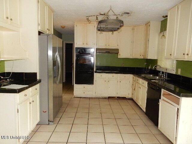 1510 Springridge Dr, Jackson, MS 39211 - kitchen featuring a sink, black appliances, under cabinet range hood, light tile patterned flooring, and dark countertops