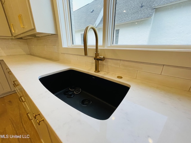 details featuring tasteful backsplash, sink, and light brown cabinets