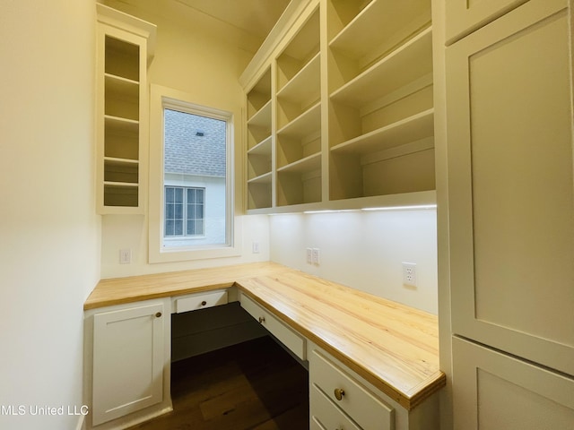 unfurnished office with dark wood-type flooring and built in desk