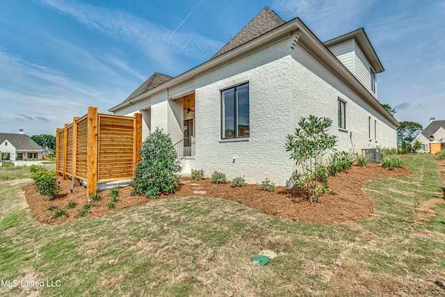 view of side of property with central AC unit and a lawn